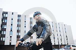 Male courier with bicycle and sunglasses delivering packages in city.