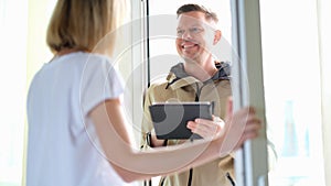 Male courier delivering package and holding tablet with data