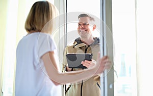 Male courier delivering package and holding tablet with data