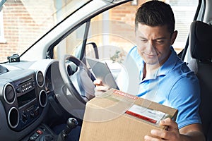 Male Courier In Van With Digital Tablet Delivering Package To House