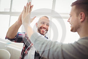 Male coworkers giving high-five