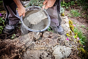 A male craftsman builds a raised bed or wall from rough stones