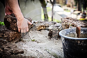 A male craftsman builds a raised bed or wall from rough stones