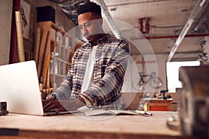 Male Craftsman In Carpentry Workshop For Bamboo Bicycles  Doing Accounts On Laptop