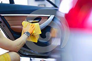 Male craftsman in gloves with microfiber wipes car handle of car closeup