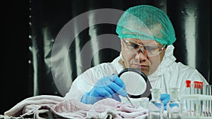Male crime lab worker examines evidence on clothes