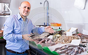 Male customer buying fish in shop.