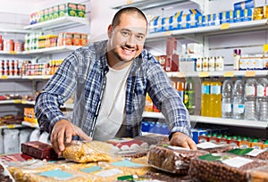 Male customer choosing nuts and grain in average food shop