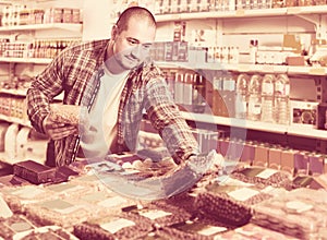 Male customer choosing nuts and grain in average food shop