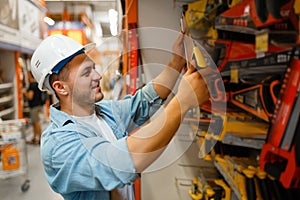 Male customer choosing saw in hardware store