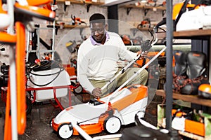 Male customer examining lawnmowers in equipment shop