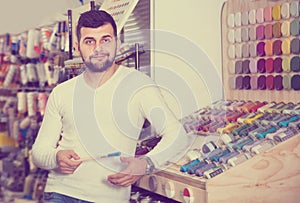 Male customer examining various types of brushes in paint store
