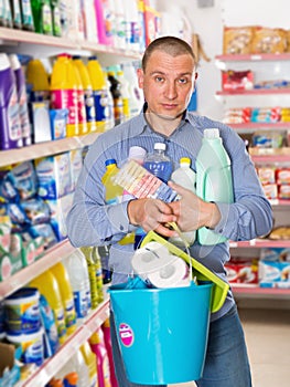 Male customer holding purchases with shopping list in household shop