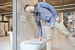 Male customer looking at toilets on sale at a modern store or shopping centre