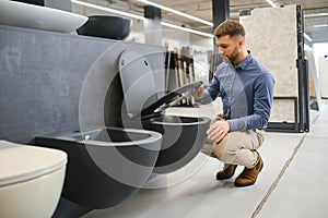 Male customer looking at toilets on sale at a modern store or shopping centre
