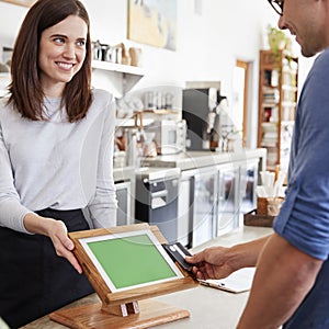 Male customer makes contactless card payment at coffee shop