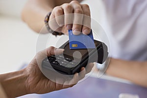 Male customer paying by contactless credit card with NFC technology
