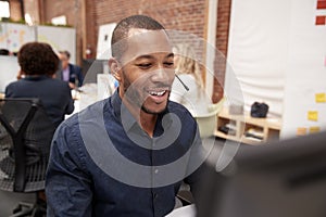 Male Customer Services Agent Working At Desk In Call Center