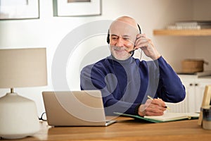 Male custormer service assistant business man wearing headset and using laptop while working from home