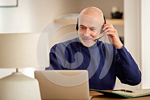 Male custormer service assistant business man wearing headset and using laptop while working from home