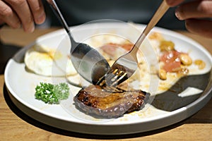 A male is cutting and eating delicious Loco moco dish