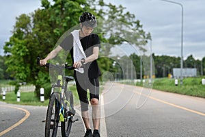 Male cyclist with injured knee carry bicycle walking in park after an accident.