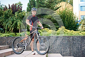 Male cyclist posing near bike on stairs