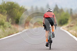Male cyclist riding racing bicycle, man cycling on countryside summer road