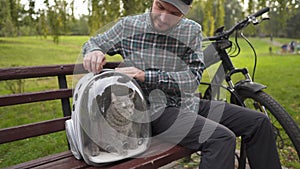 Male cyclist travels with cat in transparent backpack on mountain bike. Pet and guy friendship, love of animals. Always