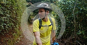 Male cyclist walking with mountain bike in forest