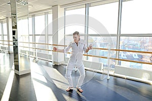 Male dancer making sweeps in black suit at studio.