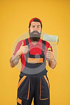 Male decorator in overall. sad bearded man worker with roller tool. hipster scene-painter yellow background. erector