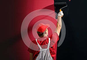 Male decorator painting a wall with black color