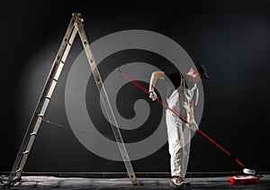 Male decorator painting a wall with black color