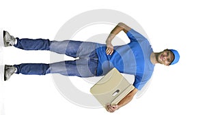 A male deliveryman, on a white background, full-length, with a box, hand on his belt