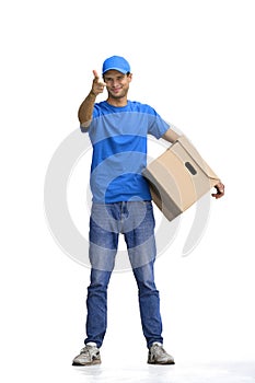 A male deliveryman, on a white background, full-length, with a box, points forward