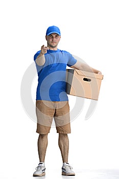 A male deliveryman, on a white background, full-length, with a box, points up
