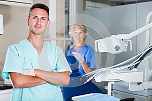 Male dentist in dental office with hands crossed