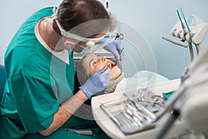 Male dentist with dental tools - mirror and probe checking up patient teeth at dental clinic office. Medicine, dentistry