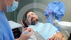 Male dentist discusses treatment with smiling male patient at modern dental clinic. Consultation of a dental surgeon