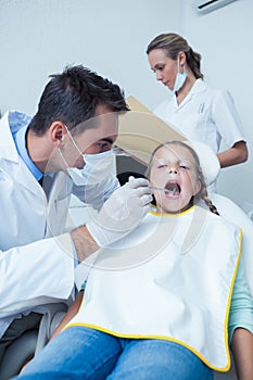 Male dentist examining girls teeth