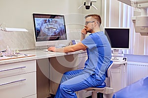 Dentist looking at teeth x-ray on the computer in a dentist office.