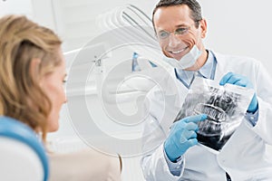 Male dentist showing female patient x-ray in modern