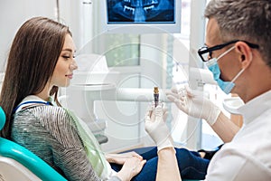 Male dentist showing his female patient a dental implant