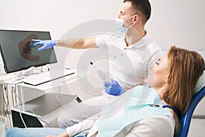 Male dentist showing results of dental 3D scanning to woman in clinic