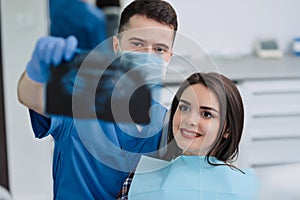 Male dentist showing x-ray to his patient in dental clinic