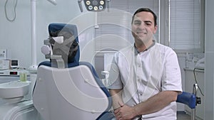 Male dentist sitting on background of dentists chair in dental office