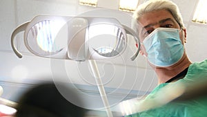 A male dentist speaking with the patient and checking his teeth, a view from the dentists chair