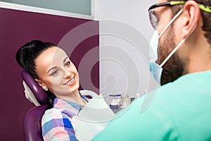 Male dentist talking to beautiful woman patient at dental clinic