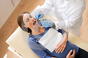 Male Dentist Treating Teeth Of Young Pregnant Woman